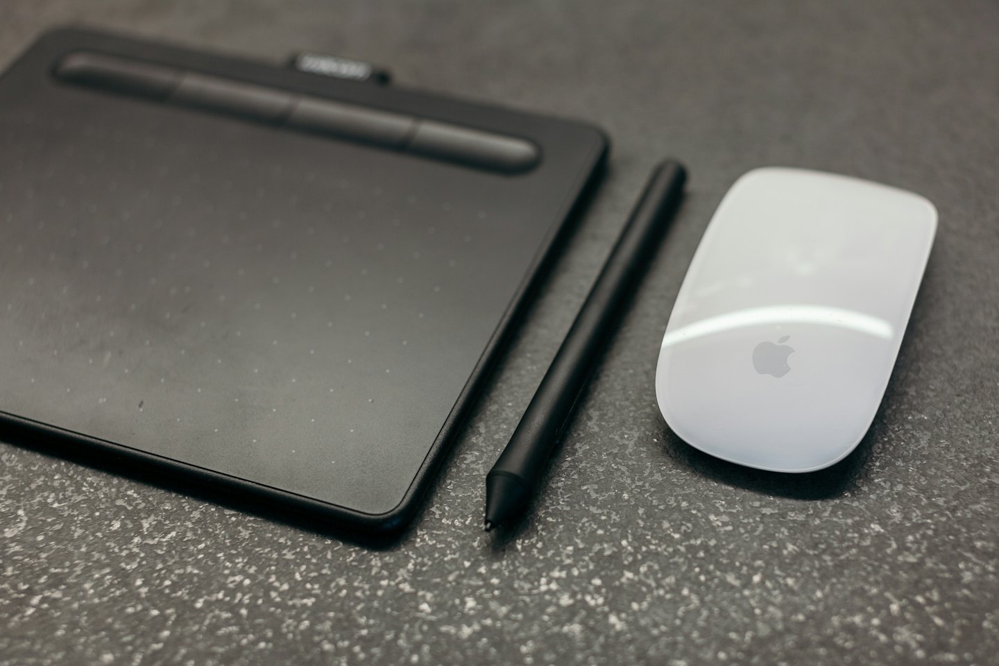 Graphic designer's tablet, stylus, and mouse on a desk.