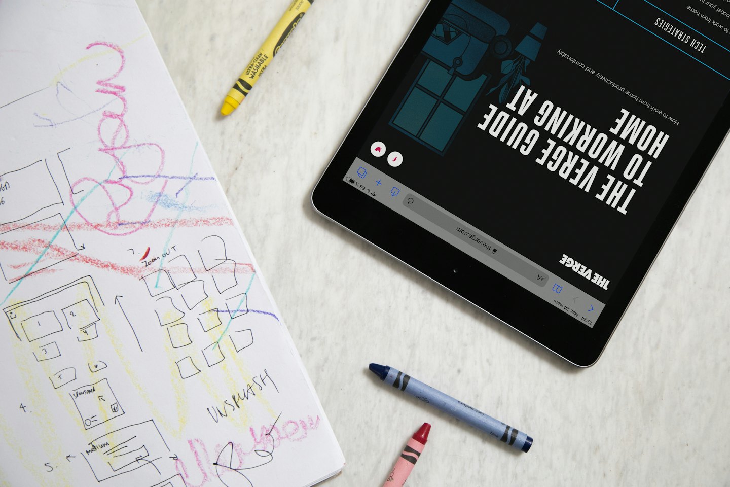 A tablet and a design sketchbook lie on a desk.